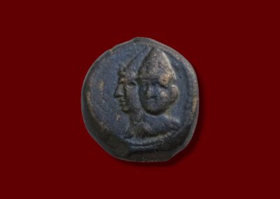 Jugate busts (side-by-side heads) of Seleucid rulers wearing helmets. Ancient Seleucid bronze coin obverse.