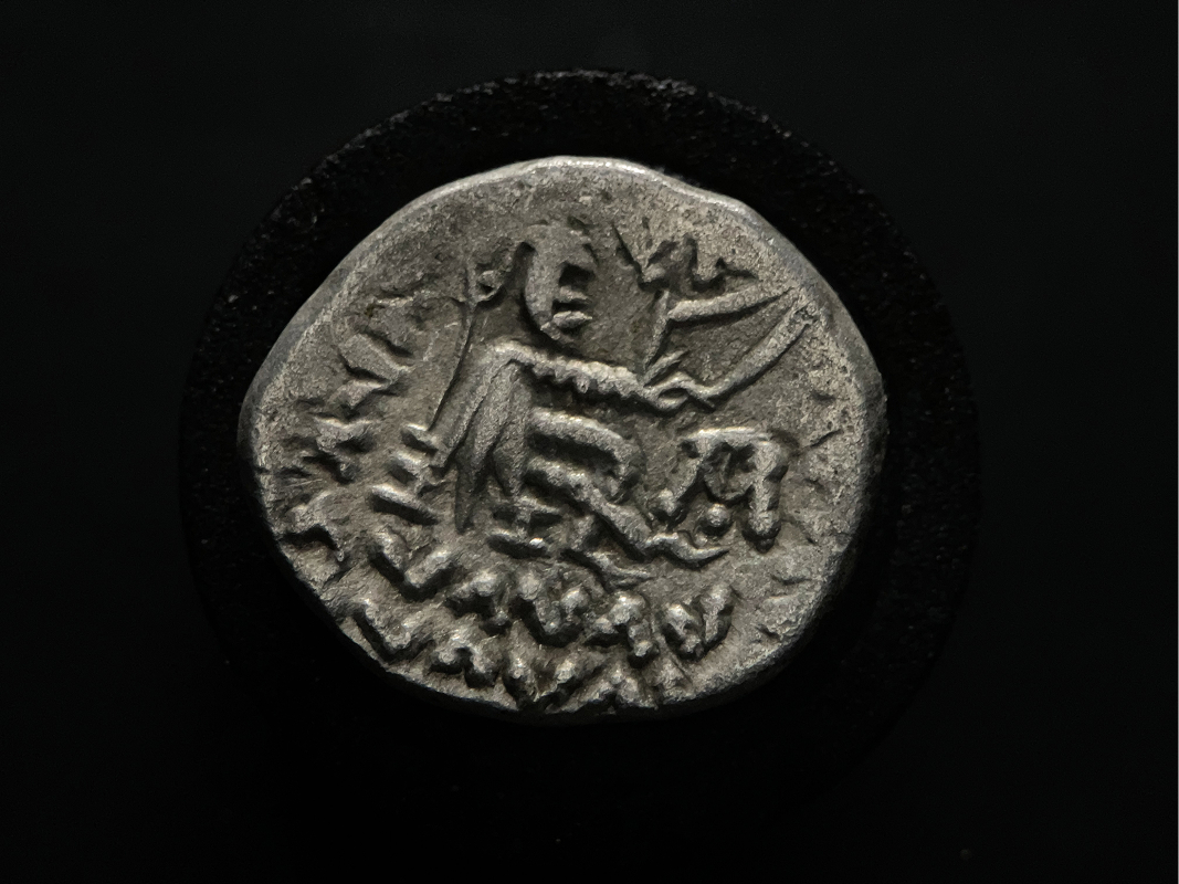 Reverse of Parthian drachm featuring seated archer and Greek inscription